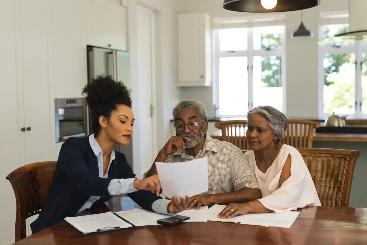 Concierge professional reviewing bills and paperwork with an older couple at their home in Dover, Delaware.
